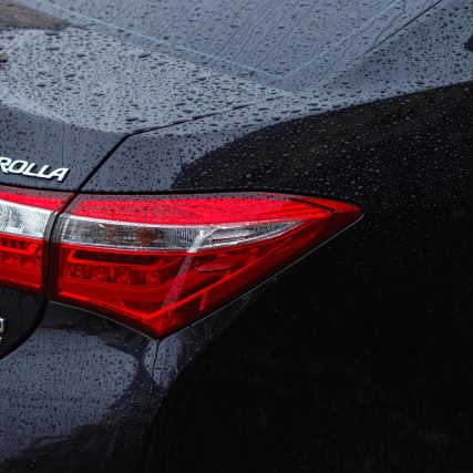 Detailed rear view of a Toyota Corolla in the rain, showcasing raindrops on the car surface.